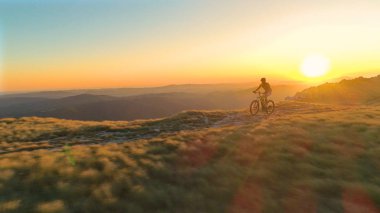 Anteni, Lens Flare: Uçan boyunca pastoral yaz gün batımında çimenli bir yol boyunca onun Bisiklete binmek bir genç adam. Akşam güneş tarafından aydınlatılmış bisikletçi ve pitoresk doğanın nefes kesen atış.