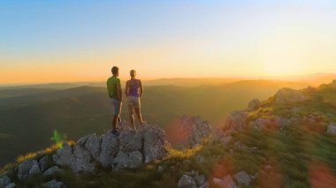 Anteni, Lens Flare, kopya alanı: Genç çift hiking Slovenya'da güneşli yaz akşamı altlarında çarpıcı yatay gözlemler. Erkek ve kadın turist doğa izlerken günbatımı aydınlatır.