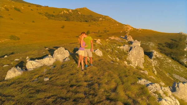 无人机 晚上的阳光照耀着男人和女人接吻后 在斯洛文尼亚美丽的山区长途跋涉 金色的日落照耀着在迷人的大自然中享受夏天的运动情侣 — 图库照片