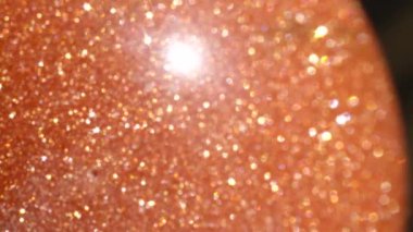 Makro Dof: Güneş ışığında parıldayan altın lekeleri ile güzel turuncu güneştaşı küre. Güneş ışığında parıldayan güneş taşı yarı değerli taş. Güçlü ışık ışınları yayan yansıtıcı altın yuvarlak taş.