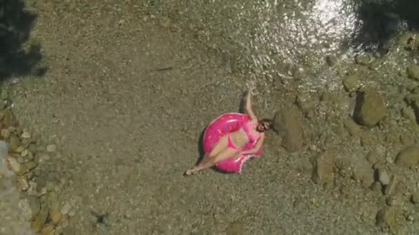 在甜甜圈浮子上的懒女轻轻抚摸水 在炎热的一天冷却下来 漂亮的布鲁内特在当地的河流放松 年轻的女性游客享受一天在阳光下河边 — 图库视频影像