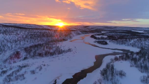 夢の夕日にラップランドの荒野で雪の冬のワンダーランドを流れる蛇行川の上を飛ぶ 黄金の日の出 フィンランドで絵のように美しい丘陵地帯を蛇行する小川 — ストック動画