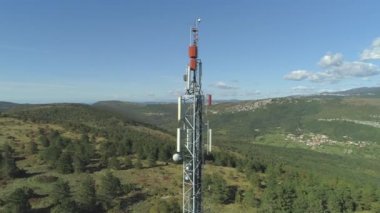 Havadan Heybetli radyo anten kulesi güneşli öğleden sonra kayalık ve yeşil karst manzara dışarı yapışmasını. Arka planda yemyeşil el değmemiş doğa ile yüksek teknoloji telekomünikasyon yapısı etrafında uçan