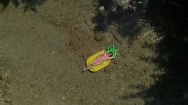 Havadan Yukarıdan Aşağıya: Güzel doğa ile çevrili yerel nehirde ananas floatie üzerinde yatan genç kadın. Güneşli açık havada nehir kenarında dinlenen rahat bir turist. Güzel esmer yaz tatili zevk.