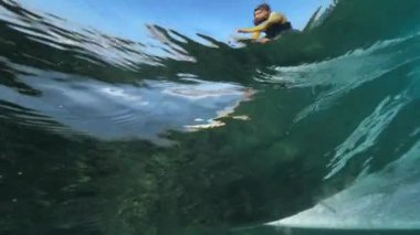 Sualtı, yavaş hareket: tehlikeli okyanus dalgaları sürme eğlenceli kolay sörfçü. Kıyıya sörf tahtasında adam taşıyan güzel mavi okyanus dalgası. Enerjik turist sörf yaparken güneşin tadını çıkarıyor.
