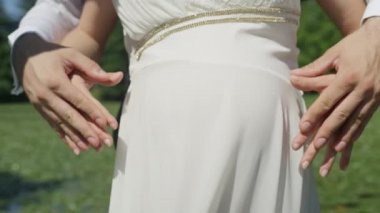 Slow Motion Close Up: Tanınmayan çift, kadının hamile karnına kalp şekli yapar. Anne-babaların yakında doğmak için heyecanlarını jestlerini bekliyorlar bebeğim. Anne-babalar çift hamilelik zevk.