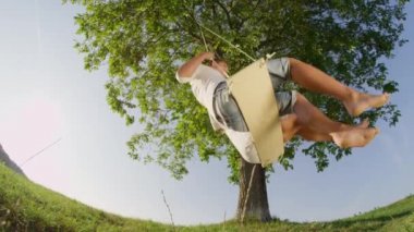 Yavaş Hareket Düşük Açı Close Up: Aşık neşeli genç adam büyük bir yeşil ağacın altında sallanan ise onun gülümseyen kız arkadaşı bakarak. Baharda kırsal da romantik bir an paylaşan güzel çift.