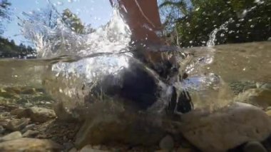 Yarım, Close Up: Soğuk su akıntıya karşı akarken ormanlık dağlarda kayalık nehir yatağına ayak basan kişi. Kristal berraklığında su sıçraması ve tanınmayan kişi olarak köpüren adım.