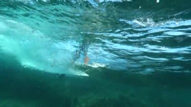 Sualtı, yavaş hareket: kıyıya sörf tahtası üzerinde tanınmaz adam taşıyan güzel okyanus dalgası. Güzel derin mavi haddeleme dalga sinematik atış. Sörfçü güneşli bir günde müthiş okyanus dalgaları sürme.