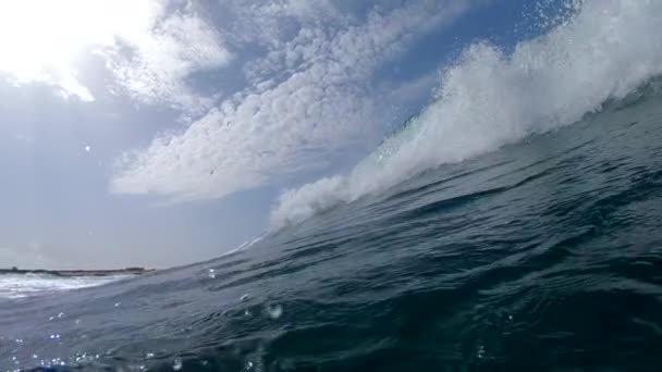 MOTION LENT SOUS L'EAU : Vagues cristallines s'approchant rapidement de la côte rocheuse. Eau de mer bleu profond moussant se précipitant vers les îles Canaries par un après-midi nuageux. Caméra plonge dans la belle mer d'émeraude .