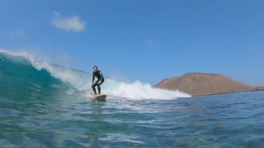 Yavaş Hareket, Düşük Açı, Sualtı Neşeli genç surfboarder Lobos müthiş dalgalar sürmek. Sörfçü volkanik ada yakınında müthiş büyük dalga sürme. Sörfçü kamera geçmiş sürmek gibi fun okyanus dalgaları sıçrayan.