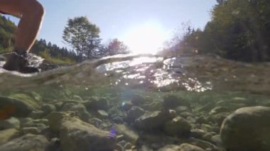 Yarım Sualtı Close Up Woman trekking ayakkabıları ile derin soğuk dağ nehri geçerken. Yürüyüş botları içinde tanınmayan kız sonbahar öğleden sonra acele nehir de ayak bulmak için büyük kayalar üzerinde adım