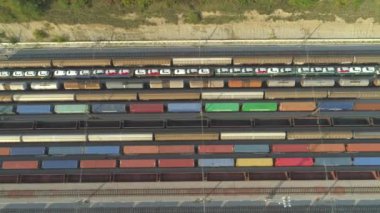 Havadan Yukarıdan Aşağıya: Güneşli bir günde kargo trenleri ve yük konteynerleri ile endüstriyel demiryolu istasyonu üzerinde uçmak. Endüstriyel demiryolu terminalinde tam dolu demiryolları ve nakliye konteyner trenleri.