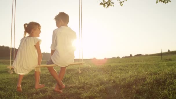 Moción Lenta Cerrar Par Niños Pequeños Charlando Alegremente Sentados Columpio — Vídeos de Stock