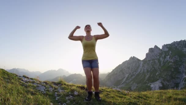 スローモーションレンズフレア 陽気な若い女性は 山の上昇を祝って 空気中に高くジャンプ 山頂に到達した後 幸せな女性ハイカージャンプとストレッチアーム トレッキングのスポーツガール — ストック動画