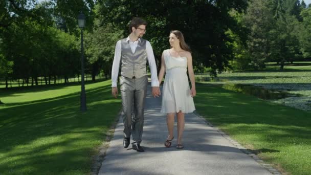 Slow Motion Happy Pregnant Couple Holding Hands Walking Trough Green — Stock Video