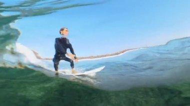 Sualtı, yavaş hareket: fit erkek sörfçü kamera lensi üzerinde harika bir camdalga sürmek. Sörf tahtası üzerinde kristal berraklığında okyanus dalgaları oyma aktif sporcu Cool yavaş çekim. Eğlenceli su sporları.