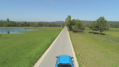 Hava Mavi araba korkunç sel sonra sonbahar doğa kurutma ile çalışan dar bir yolda sürüş. Hatchback'teki insanlar yıkıcı fırtınanın sonuçlarını araştırıyorlar. Sular altında kalan tarlaların üzerinde gezinme