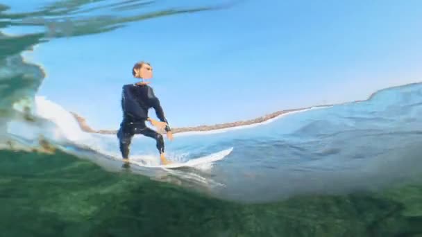 スローモーション フィット男性サーファーは カメラのレンズの上に素晴らしいガラスの波に乗ります サーフボード上の透明な海の波を彫刻アクティブなスポーツマンのクールなスローモーションショット 楽しいウォータースポーツ — ストック動画