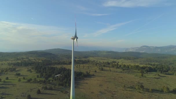 在阳光明媚的春天的早晨飞过旋转的风力涡轮机 金属风车螺旋桨在大自然中的强风中旋转 孤式风力涡轮机为周边农场提供可持续能源 — 图库视频影像