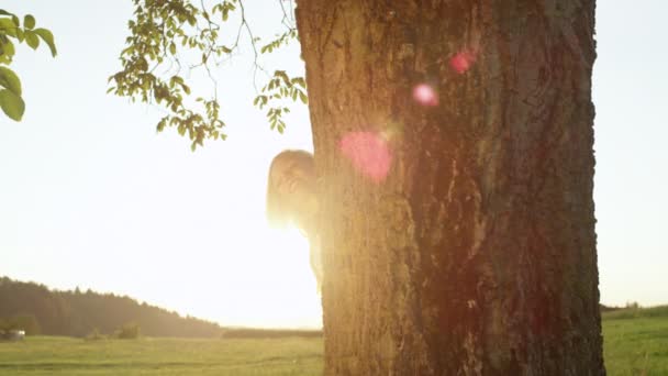 SLOW MOTION CLOSEUP Couple souriant regardant par derrière un arbre souriant pour la caméra — Video