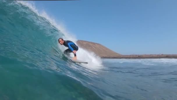 慢动作 年轻的冲浪者骑着管波 相机浸入水中 在阳光明媚的加那利群岛 男性冲浪者在他的冲浪板上冲浪 男性冲浪者在阳光下雕刻波浪的慢动作 — 图库视频影像