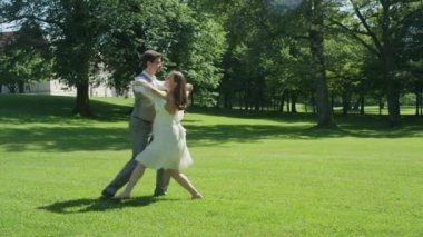 Slow Motion Mutlu genç adam ve eşi güneşli bir yaz gününde açık havada vals. Yeni evli çift doğanın sesleri parkta ilk dans paylaşmak. Hamile kadın yalınayak dans sahiptir.