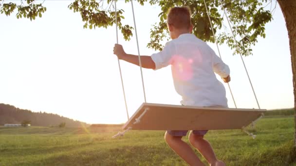 Movimiento Lento Cerrar Niño Irreconocible Balanceándose Sobre Columpio Madera Atardecer — Vídeos de Stock