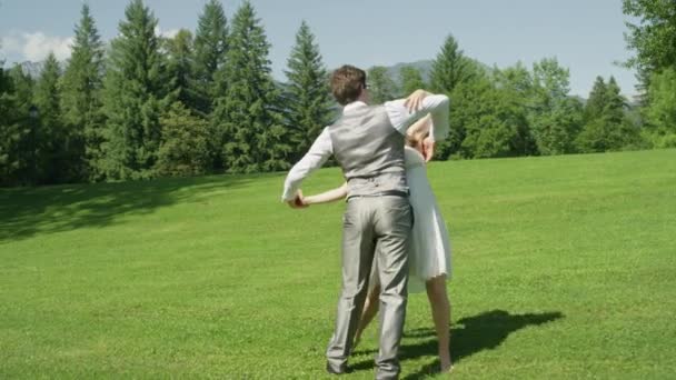 スローモーション新婚夫婦は 結婚式の後 公園で楽しく踊ります 晴れた日に草の上でワルツを振る若い男女 夫は彼の美しい妻を回転させ 彼らはダンスの終わりにお辞儀 — ストック動画