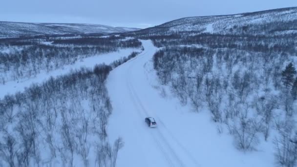 在森林雪山底部风景秀丽的乡村公路上行驶的汽车上方 穿越芬兰拉普兰的公路旅行 汽车穿越寒冬荒野 — 图库视频影像