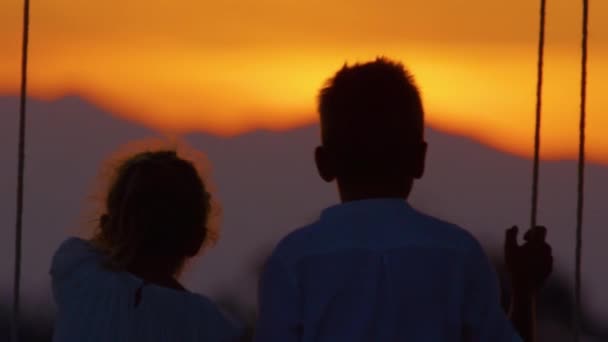 Slow Motion Silhouette Close Två Barn Tittar Solnedgången Medan Svänger — Stockvideo