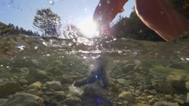SLOW MOTION, HALF UNDERWATER Personne méconnaissable traversant la rivière avec des bottes d'alpinisme. Randonneuse traversant une rivière peu profonde avec des bottes de montagne en cuir. Les gens trekking sur la rivière rocheuse 