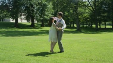 Slow Motion Mutlu genç adam ve eşi güneşli bir yaz gününde açık havada vals. Yeni evli çift doğanın sesleri parkta ilk dans paylaşmak. Hamile kadın yalınayak dans sahiptir.