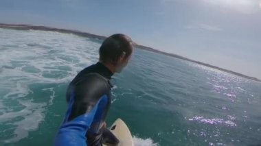 Yavaş Hareket Selfie: Neşeli sörfçü dalgalar sürme, güneşli denizde goofy yüzleri yapıyor. Profesyonel sörfçü güneşli Fuerteventura dalgalar sörf ve kristal berraklığında okyanusa atlama. Suya düşen oyuncu adam.
