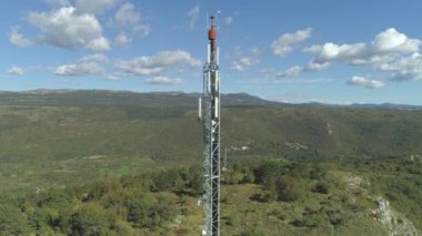 Havadan Uzun Gsm anten kulesi güneşli yaz gününde ormanlık karst manzara üzerinde başgösteren. Uzak alanda yüksek hızlı uluslararası veri aktarımı sağlayan yüksek teknoloji telekomünikasyon pilonu