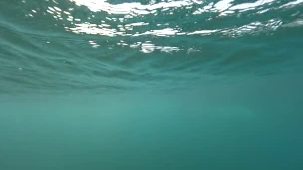 スローモーション水中 太陽の下で輝く海面のようなガラスの上に形成される小さな波 ロボス島の深い青い水中世界 海の動きを生み出す自然の魅惑的な力 — ストック動画