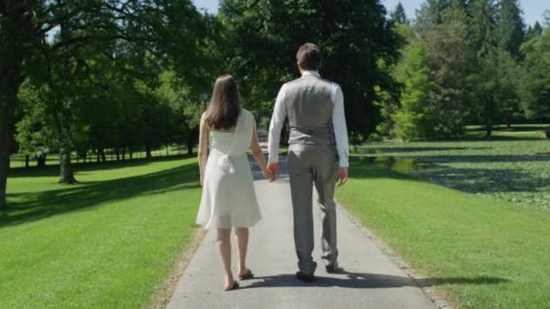 Slow Motion Happy Pregnant Couple Holding Hands Walking Trough Green — Stock Video