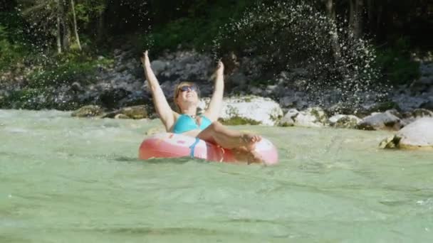 Lento movimiento río deslizamiento chica en donut floatie salpicaduras de agua en el aire — Vídeo de stock