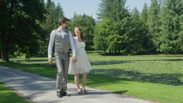 Slow Motion Happy Pregnant Couple Holding Hands Walking Trough Green — Stock Video