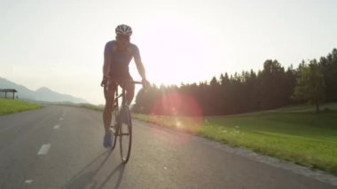 Atletik genç erkek yoğun dağ yarışı sırasında onun serin yol bisikleti pedallar üzerinde adım. Güneşli dağlarda Pro yol bisikletçi eğitimi. Yaz doğasında pitoresk bisiklet yolculuğu. Yavaş hareket görüntüleri
