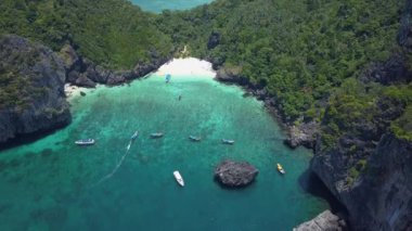 Hava: güneşli turist beach Tayland yakınındaki gür tropikal yeşil kaplı büyük kalker uçurum boyunca uçan. Büyük karstik oluşumu uzak beach yaklaşan mavi okyanus dalgaları üzerinde yükselir.
