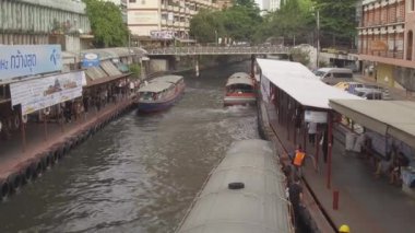Bangkok, Tayland - Mart 2017 Hava: Kirli Chao Phraya nehri üzerinde kalabalık su taksi trafiği ve yerliler ve turistlerle dolu iskeleler serin çekim. Nehir kenarı Tayland ulaşım Yerel ortalama. 
