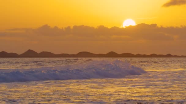 慢动作 在金色的夏日夜晚 来自海洋的泡沫水净化岩石黑色海滩 五颜六色的夏日日落照亮了美丽的海军景观 海滩上的橙色夜晚 — 图库视频影像
