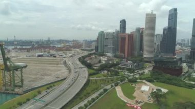 Yolun diğer tarafında iş bölgesi ile marina tarafından Singapur otoban üzerinde Uçan Hava. Gökdelenler şehir merkezinde yükseliyor. Bulutlu günde metropolün işlek yolları. Rıhtımlarda büyüyen sanayi