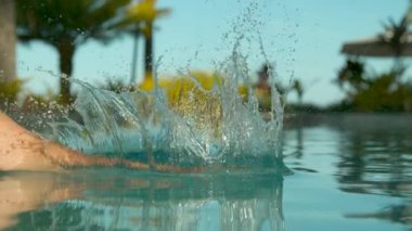 Slow Motion, Close Up: Egzotik havuzda rahatlatıcı dalış genç gezgin etrafında her yerde su sıçramaları. Sayısız su damlacıkları yüksek son tatil beldesinde tropikal havuz etrafında her yerde uçmak.