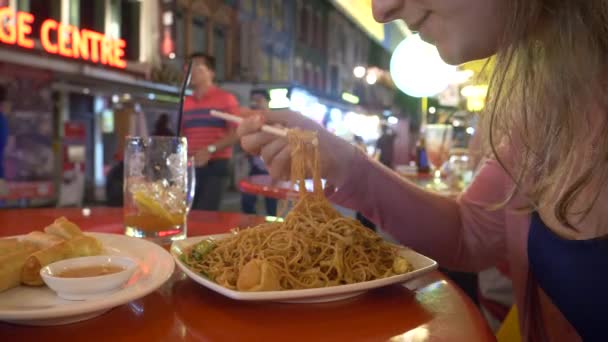 クローズアップ チョップスティックでアジアンヌードルの食事を食べようとしている若い女性観光客 箸でアジア料理を食べる方法を学ぶ女の子旅行者 食品市場で食べる認識できない白人女性 — ストック動画