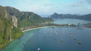 Hava: güneşli turist beach Tayland yakınındaki gür tropikal yeşil kaplı büyük kalker uçurum boyunca uçan. Büyük karstik oluşumu uzak beach yaklaşan mavi okyanus dalgaları üzerinde yükselir.