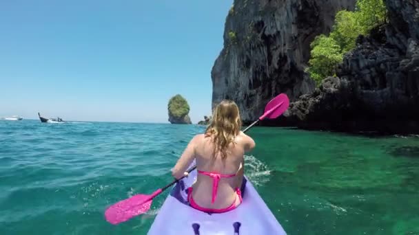 活跃的高加索女孩在真棒假期划桨她的皮划艇到壮观的沙滩 穿着比基尼的女游客在华丽的绿松石海水中划水 经过尖锐的岩石小岛 — 图库视频影像