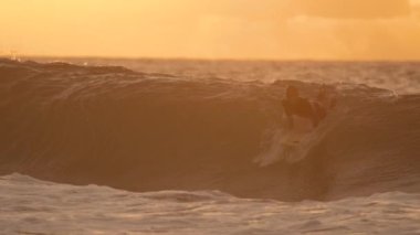 yavaş hareket: serin sörfçü onun kurulu üzerinde ayağa kalkar ve gün batımında bir tüp dalga sürmek. Tanınmayan adam bir resim mükemmel bir yaz akşamı müthiş okyanus dalga sörfü. Dokunaklı manzarada tatil eğlencesi