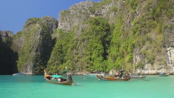 航空写真 タイで日当たりの良い観光ビーチ近く緑豊かな熱帯の緑で覆われて大規模な石灰岩の崖に沿って飛行 巨大なカルスト形成が上がる青い海の波遠くのビーチに近づいて — ストック動画